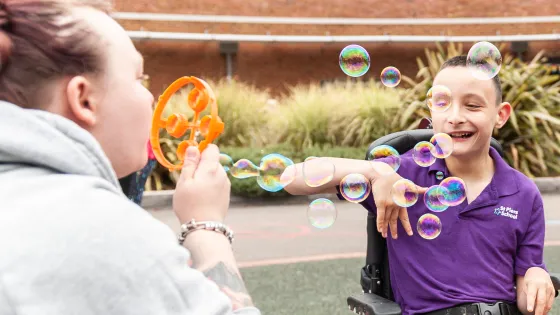 student smiling whilst blowing bubbles