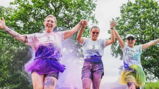 Three young women are covered in paint on a colour run.