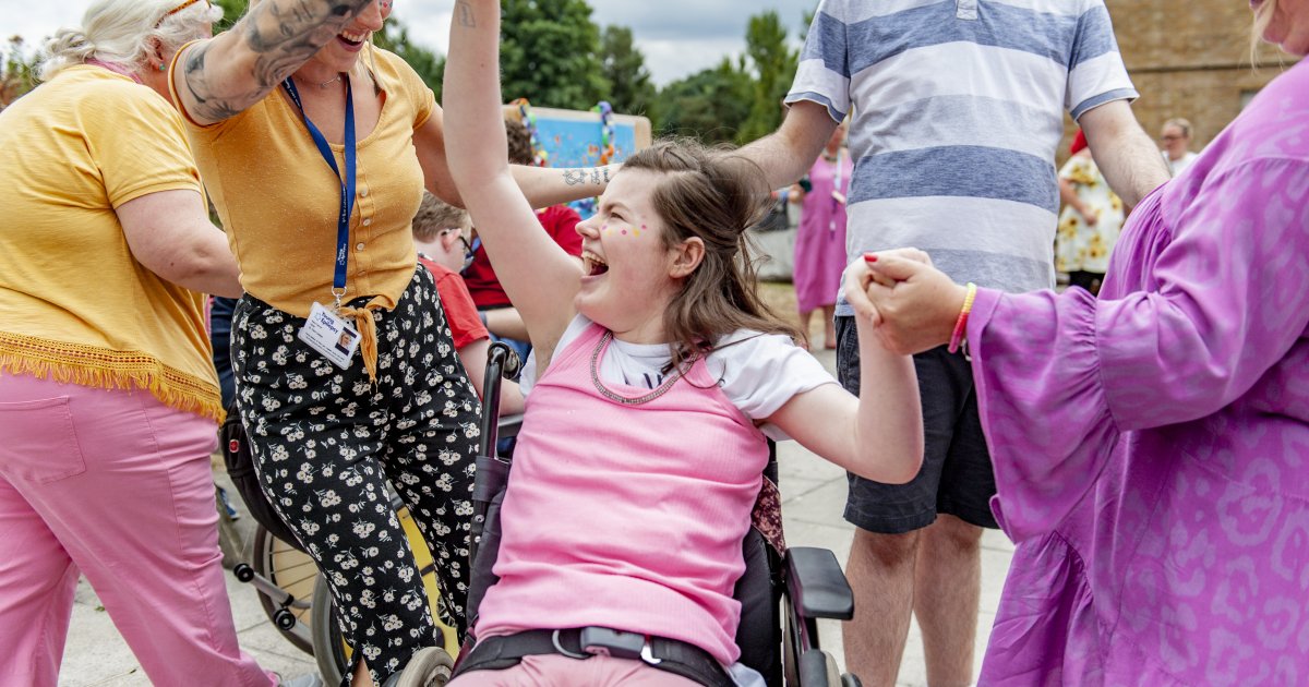 female student laughing in her wheelchair and dancing