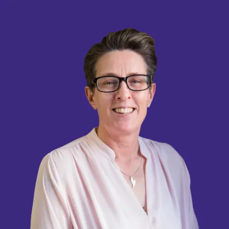 Short haired lady with light pink blouse and glasses smiling