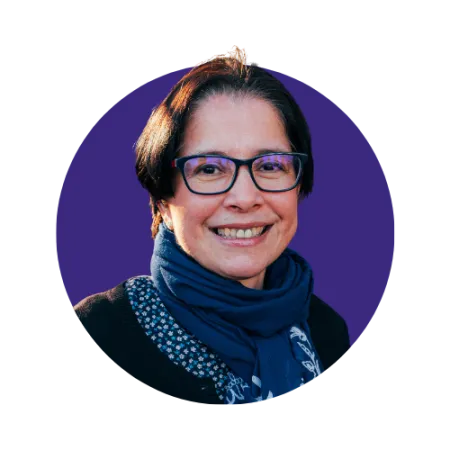 Short dark haired lady smiling with glasses and a scarf